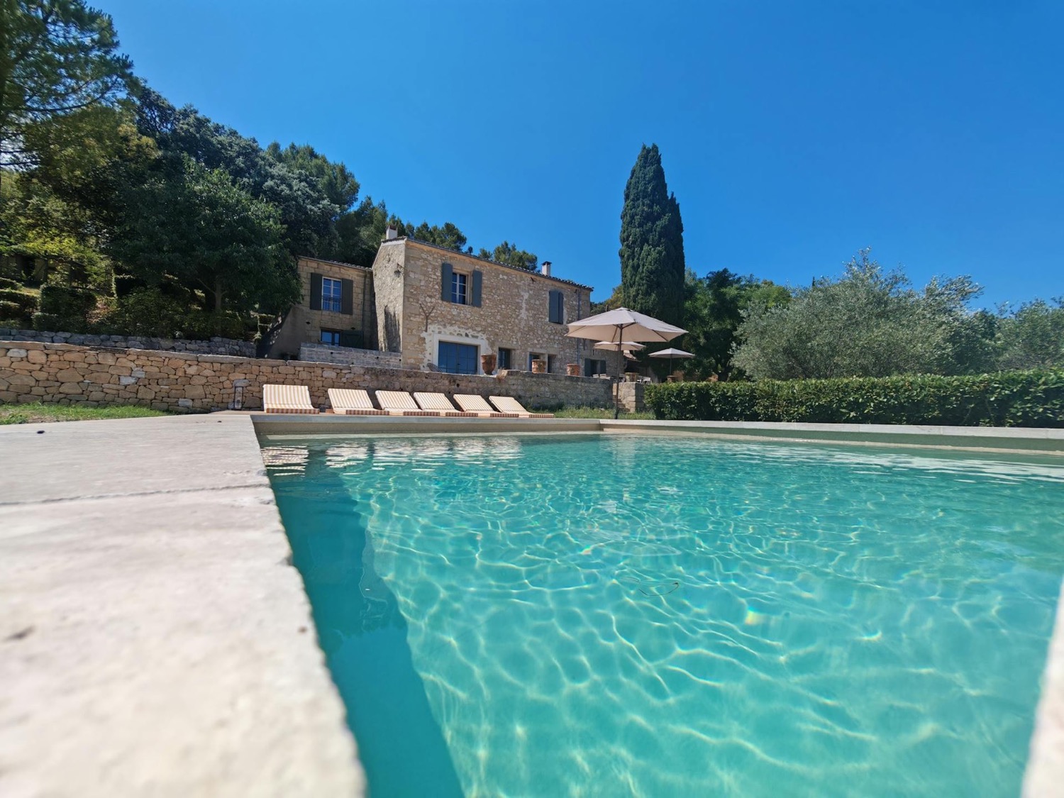 Piscine de la villa en pierre, transats et cyprès