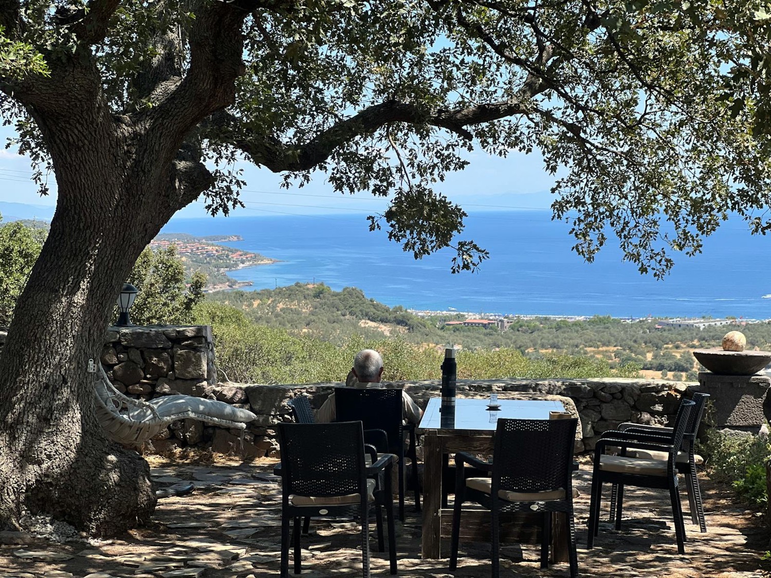 Terrasse en pierre sous un chêne, vue sur la baie